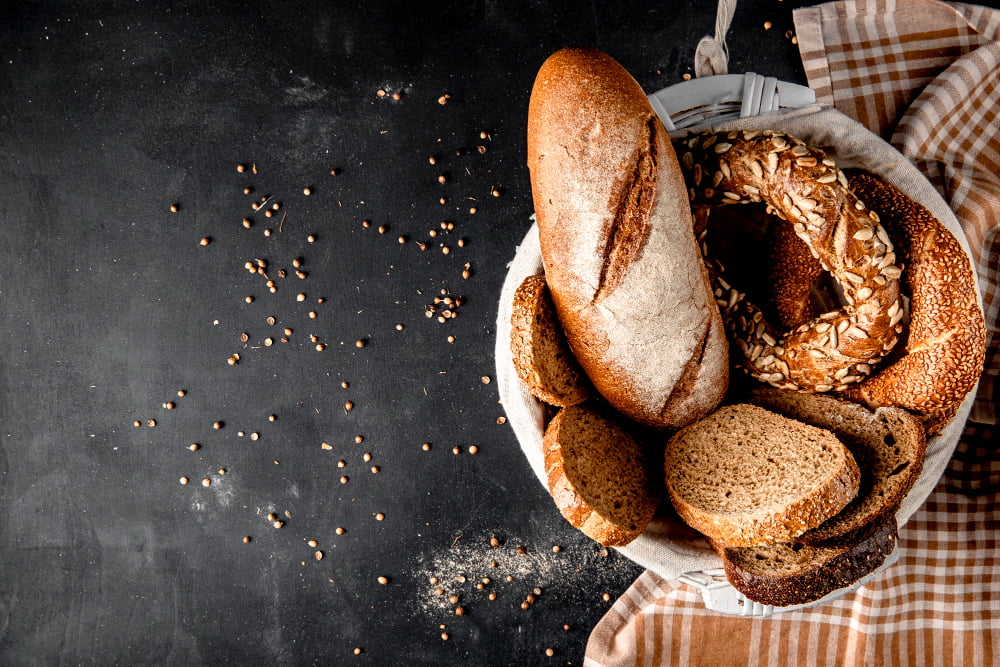 Alimentos que combatem a anemia 3 top view basket full breads as baguette bagel rye with sunflower seeds black surface