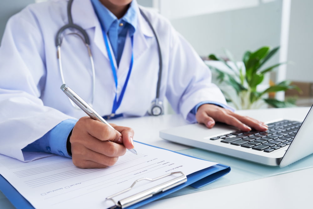Cirurgia peniana: Quando é necessário e quais os tipos? 2 hands unrecognizable female doctor writing form typing laptop keyboard 2